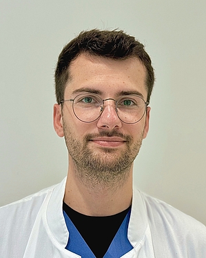 junger Mann im weißen Kittel mit Brille