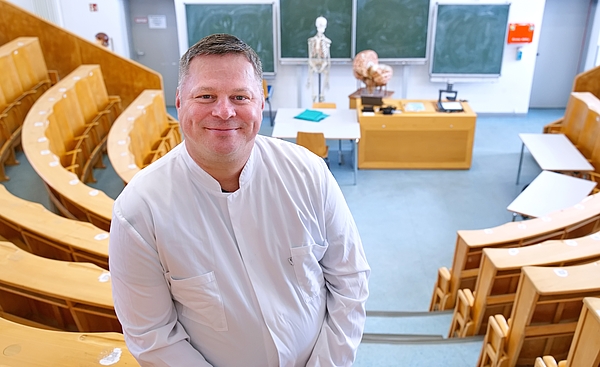 Institutsdirektor in den oberen Rängen des Hörsaals mit einem breiten Grinsen.